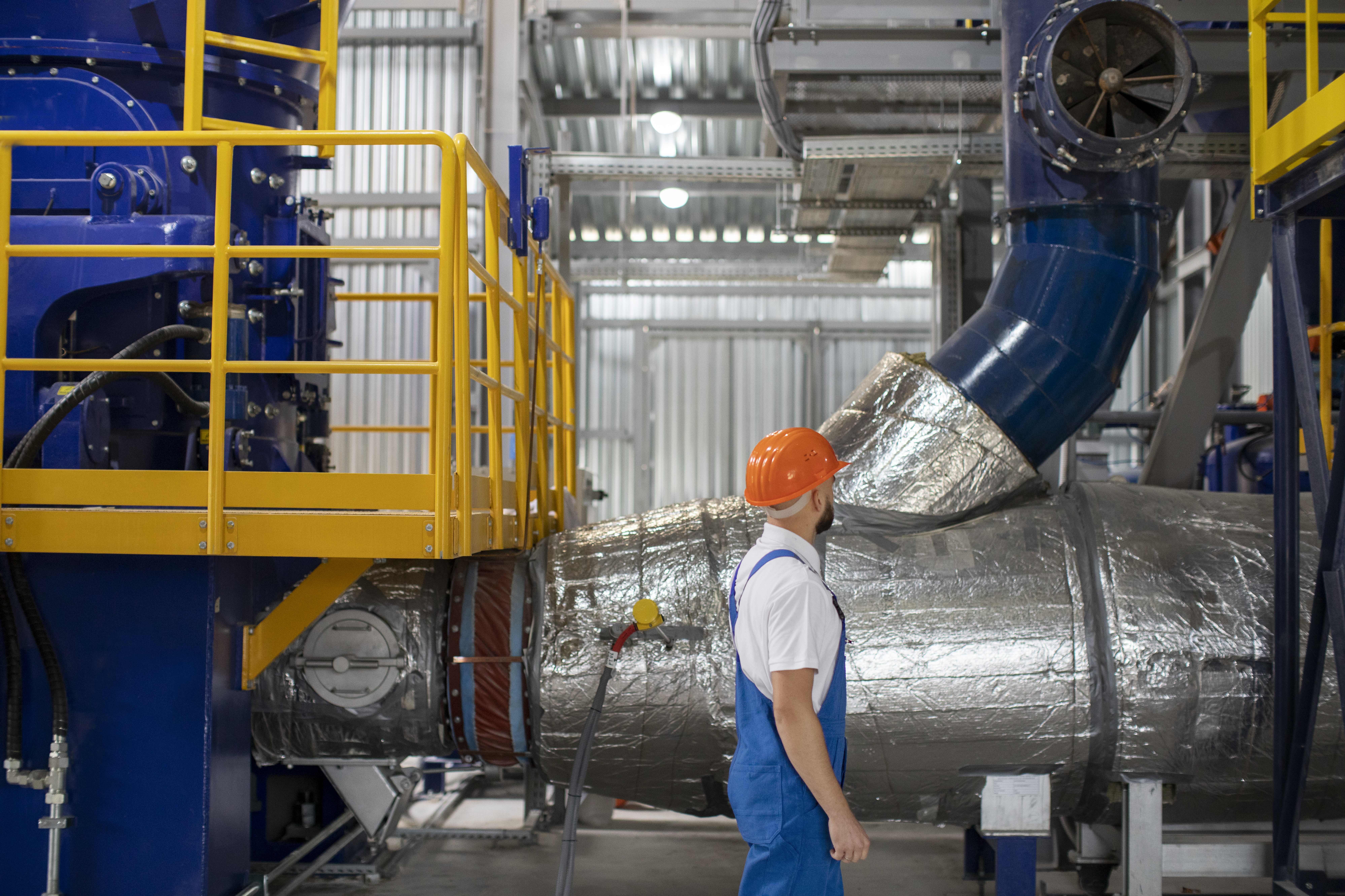 Engineer inspecting large industrial HVAC ducting and equipment inside a pharmaceutical or manufacturing facility.
